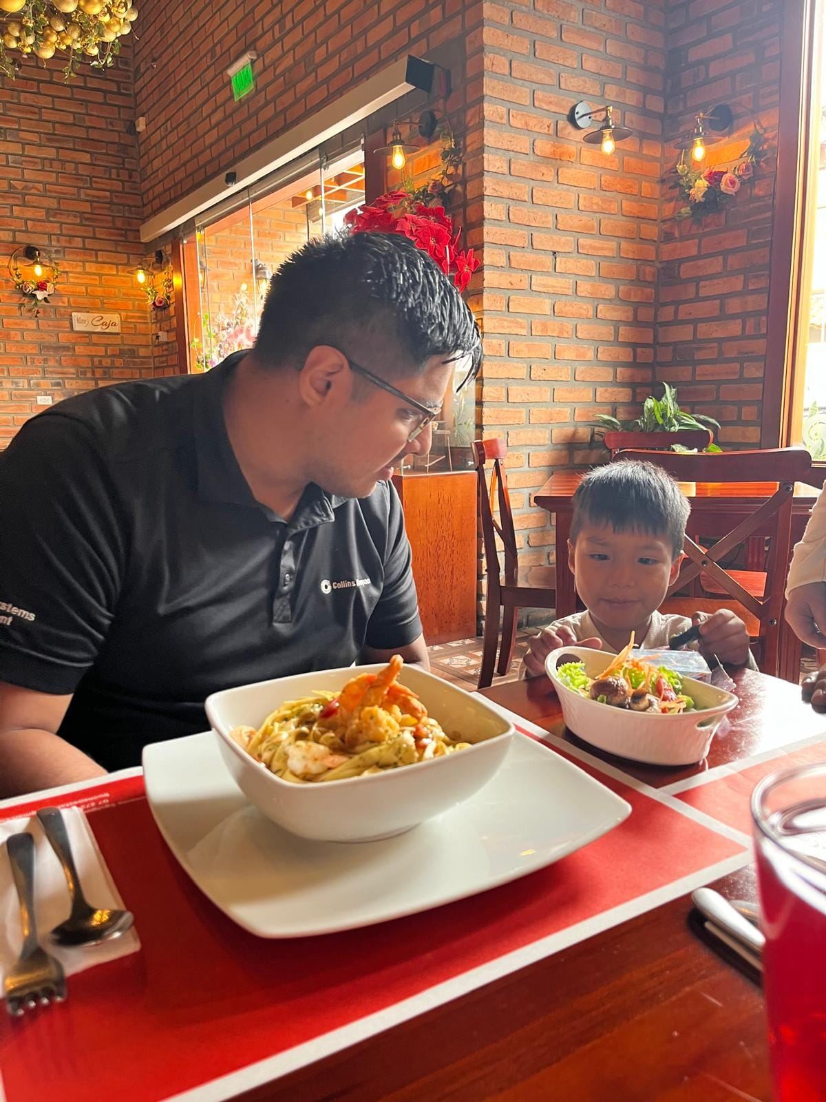 Padre e hijo disfrutando pasta de camarones en La Buona Pasta