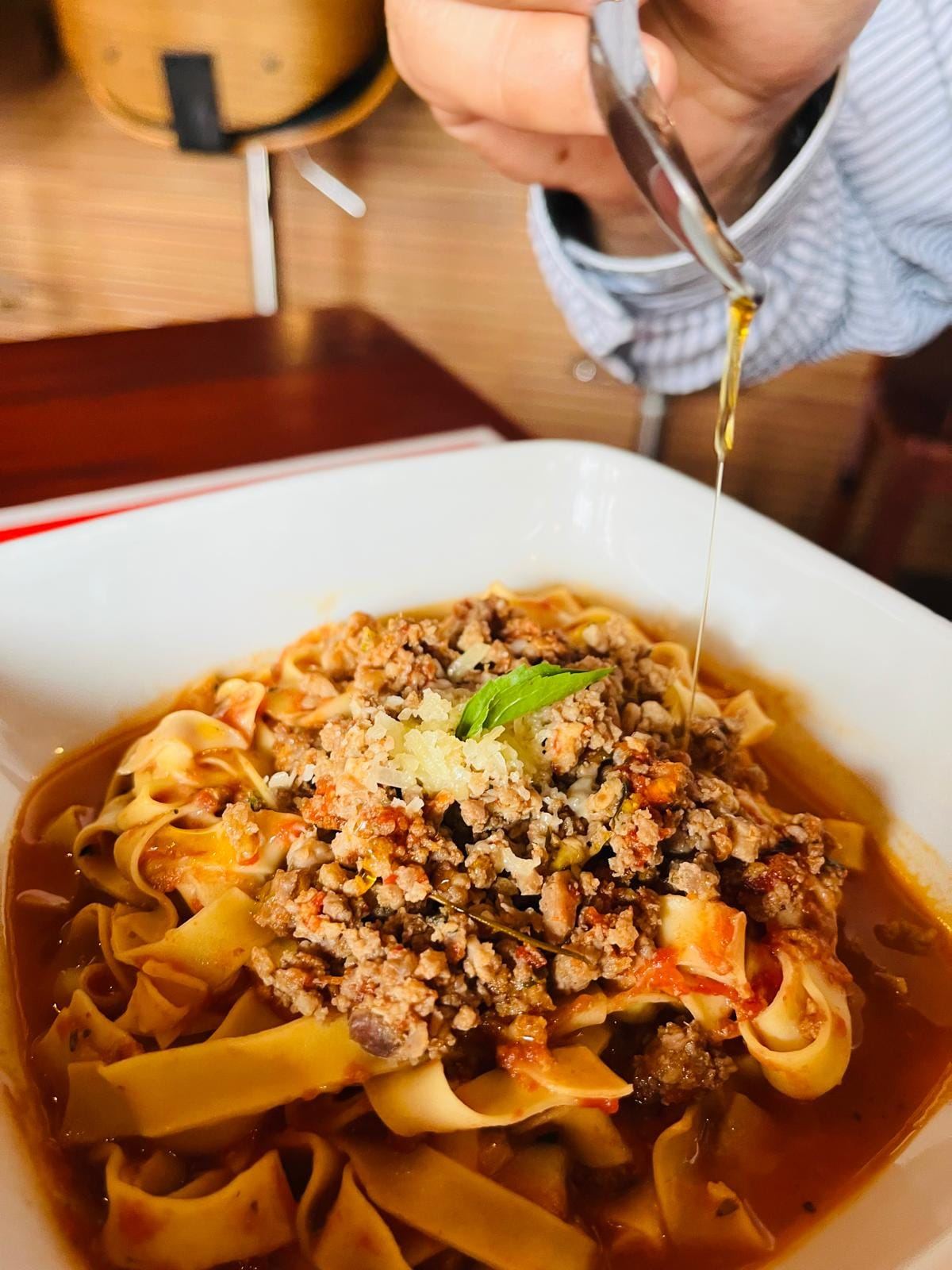 Pappardelle bolognese con parmesano fresco y albahaca, bañada en aceite de oliva