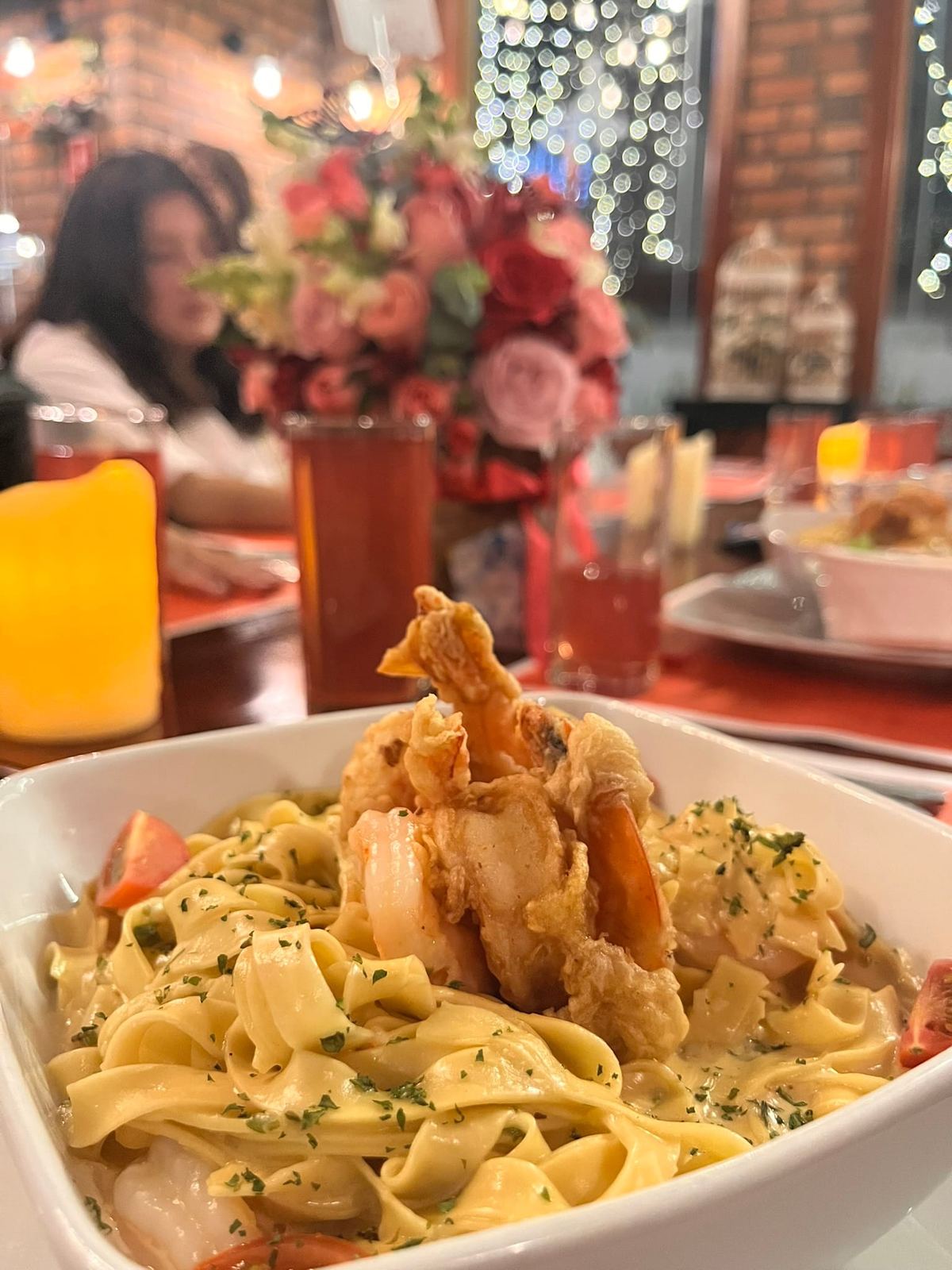 Fettuccine con camarones crujientes y luces calidas del restaurante